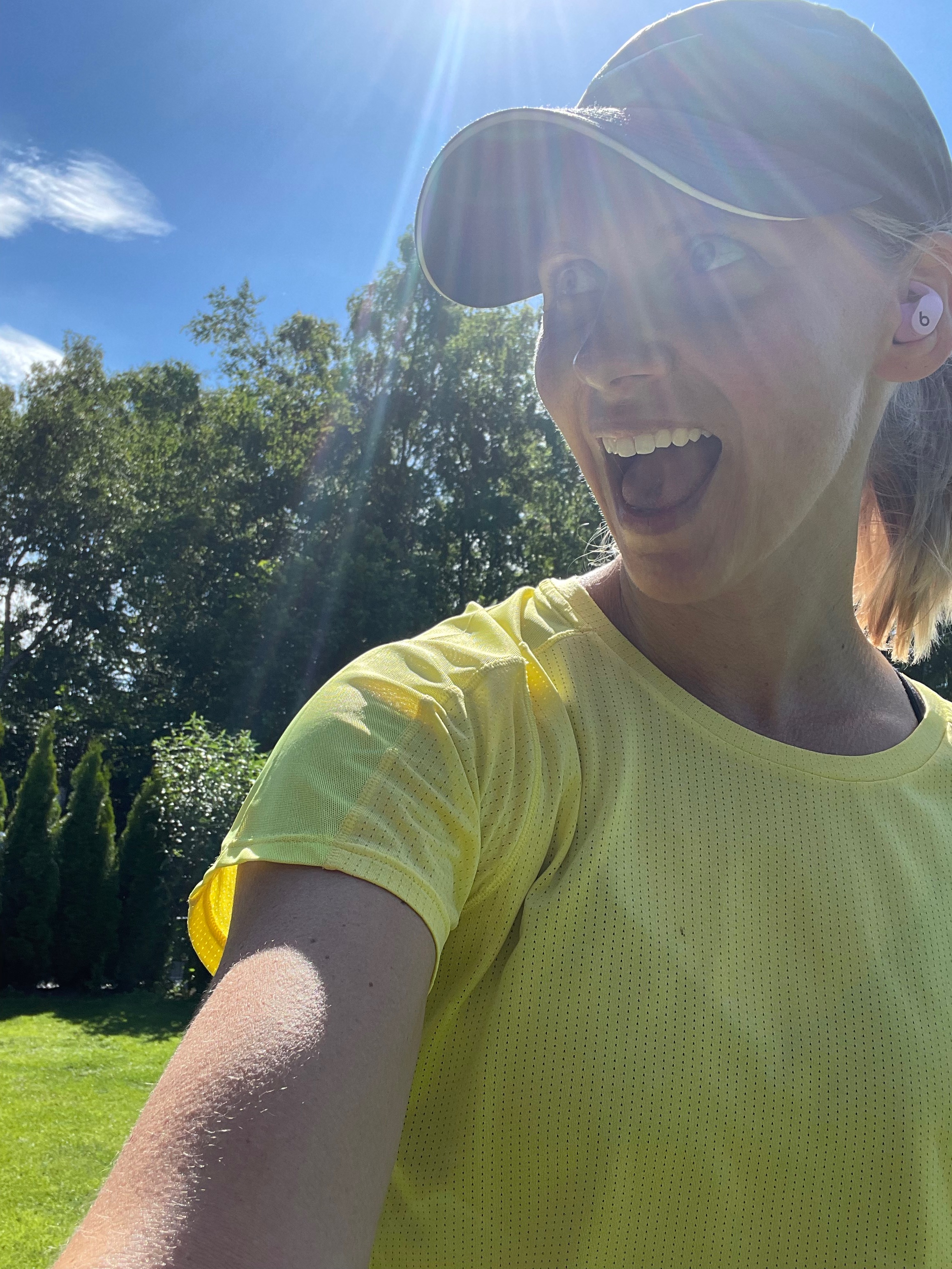 Coach Mandy laughing outdoors in a yellow shirt and cap